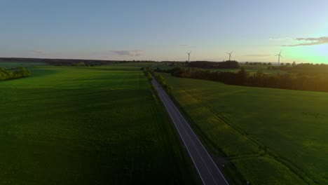 Aerial-Drone-Over-Green-European-Countryside-At-Sunset-With-Wind-Turbines-In-Distance-In-Czech-Republic