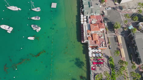 Flying-Above-Turquoise-Shoreline-of-Catalina-Island,-Drone-Flight-Over-Boats-and-Buildings-in-Avalon-Harbor