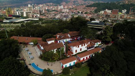 Complejo-Residencial-En-Una-Colina-Cubierta-De-árboles-Gruesos-Sobre-La-Ciudad-De-Medellín-Con-Piscina-Y-Gente-Que-Pasa---Colombia