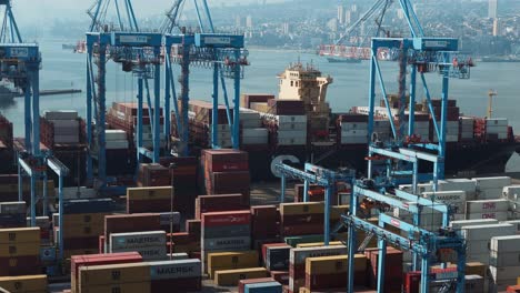 Jib-up-of-containers-stacked-near-cranes-ready-to-be-loaded-on-a-cargo-ship-docked-in-Valparaiso-Sea-Port,-Chile