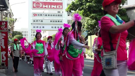 Asiatische-Tänzer-Winken-Während-Der-Straßenparade-Mit-Großen-Rosa-Bändern
