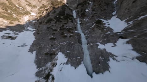 Fpv-Drone-Volando-Sobre-Una-Cascada-Congelada-En-Una-Montaña-Austriaca-En-Primavera-Al-Atardecer