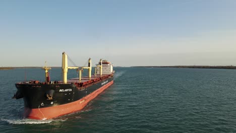 Aerial-Backwards-low-angle-following-shot-of-Freighter-on-Detroit-River-near-Wyandotte-Michigan-in-USA