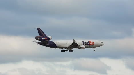 Following-side-view-of-FedEx-airplane-in-cloudy-sky-descending