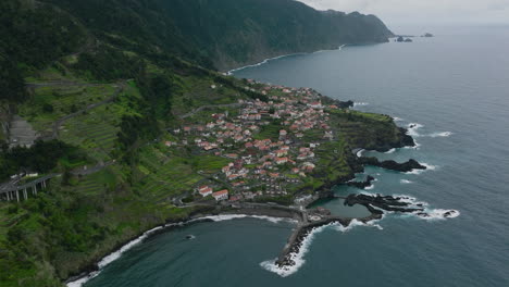 Luftaufnahme-Des-Schwarzen-Sandstrandes,-Des-Piers-Und-Des-Natürlichen-Gezeitenpools-In-Seixal,-Madeira