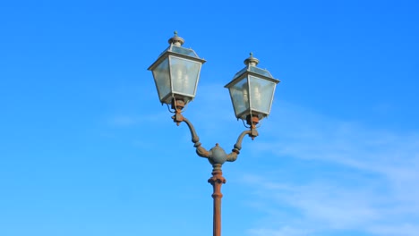 Panning-across-typical-Italian-street-lamp-on-clear-blue-sky-in-Naples,-Italy