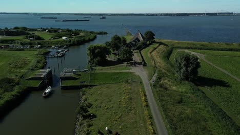 Drohnenaufnahmen-Eines-Schiffes,-Das-Zur-Hafenmündung-Fährt,-Um-Das-Dorf-Numansdorp-In-Den-Niederlanden-Zu-Verlassen