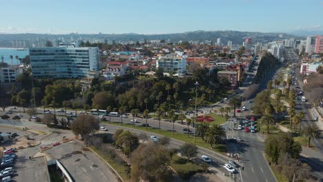 Aerial-dolly-in-over-Viña-del-Mar-city-buildings-and-luxury-resorts,-traffic-in-avenues-and-hills-in-background,-Chile