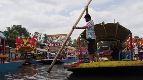 Gondolier-Using-Wooden-Rowing-Oar-To-Push-Gondola-Carrying-Tourists-Along-The-Xochimilco-Canals-Towards-Embarcadero-Nuevo-Nativitas