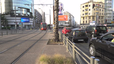 Casablanca-red-tram-line-1-living-Abdelmoumen-boulevard-to-go-downtown,-cars-waiting-at-roundabout