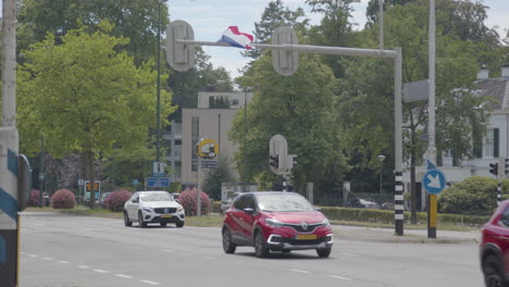 Upside-down-Dutch-flag-hanging-on-traffic-light-with-traffic-passing-underneath