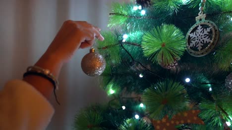 Nahaufnahme-Der-Hand-Eines-Mädchens,-Die-In-Zeitlupe-Eine-Weihnachtskugel-Auf-Den-Weihnachtsbaum-Legt