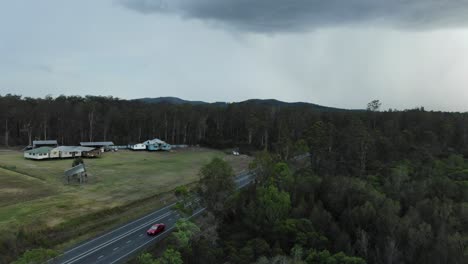 Stormy-weather-over-traditional-country-style-Australian-bungalows-and-cars-and-trucks-traffic-in-Queensland-countryside,-Australia