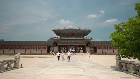 Tourists-in-protective-masks-sightseeing-near-Geunjeongmun-gate-in-Gyeongbokgung-Palace-on-clear-sky-day