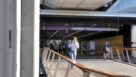 Canary-Wharf,-London,-United-Kingdom---August-2022---A-man-is-walking-out-from-the-new-Elizabeth-Line-station-in-Canary-Wharf-while-eating-a-snack-on-his-way-to-or-from-work