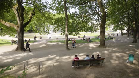 Wide-angle-view-of-people-relaxing-at-the-Jubelpark-with-water-fountain,-summer-in-the-Belgian-capital-of-Brussels,-Belgium