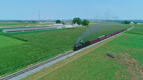 An-Aerial-View-of-an-Antique-Steam-Passenger-Train-Approaching-Blowing-Smoke-and-Steam-Traveling-Thru-Fertile-Corn-Fields-on-a-Sunny-Summer-Day