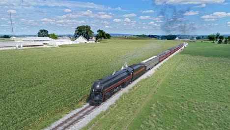 An-Aerial-View-of-an-Antique-Steam-Passenger-Train-Approaching-Blowing-Smoke-and-Steam-Traveling-Thru-Fertile-Corn-Fields-During-the-Golden-Hour-on-a-Sunny-Summer-Day