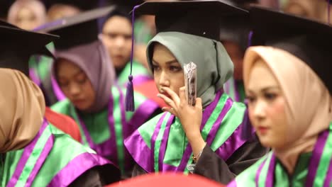 College-students-dressed-in-cap-and-gowns-listen-to-a-speech-during-a-graduation-ceremony