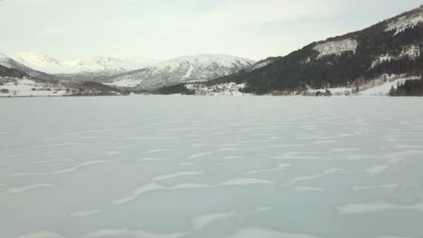 Vista-Aérea-De-Un-Lago-árido-Y-Congelado-En-Noruega-Con-Pequeñas-Olas-De-Nieve-En-La-Superficie,-Movimiento-De-Drones-Hacia-Adelante
