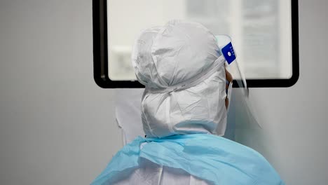 Asian-Woman-Wear-PPE-Look-Inside-Operating-Room-Window,-Close-Up