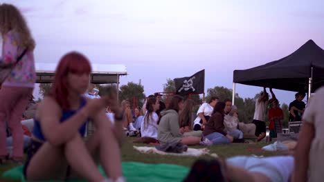Menschen-Sitzen-Auf-Dem-Festival-Mit-Der-Piratenflagge-Im-Wind,-Die-Am-Schiff-Aufgehängt-Ist