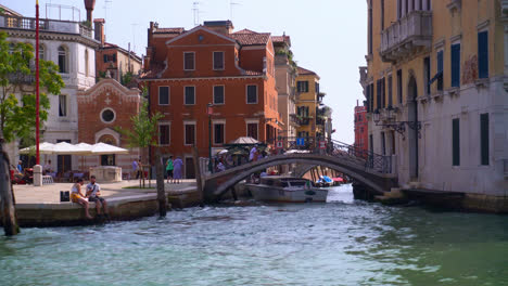 Boat-Passing-Under-Pedestrian-Bridge-On-Canal-Grande-In-Campo-San-Vio,-Venice,-Italy