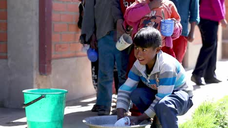 After-lunch-break,-children-at-a-school-in-the-Bolivian-Andes-Mountains-wash-their-mugs-and-spoons