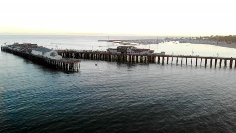 Luftdrohne,-Die-Bei-Sonnenuntergang-Mit-Segelbooten-Im-Hafen-Von-Santa-Barbara,-Kalifornien,-über-Dem-Stearns-Wharf-Pier-Fliegt