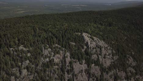 Aerial-Drone-Shot-Orbiting-Around-Rocky-Cliff-Edge-Of-Mountain-Forest