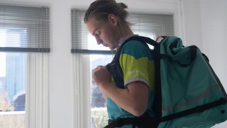 Clip-of-a-deliveroo-rider-while-wearing-his-official-backpack-during-a-sunny-day-in-his-house
