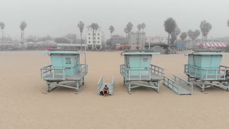 Flying-between-two-lifeguard-stands-on-Venice-Beach,-CA-in-a-thick-marine-layer