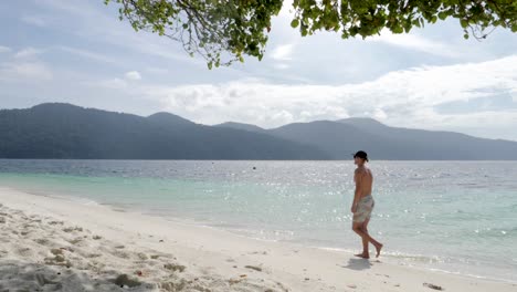 Ultrazeitlupenaufnahme-Eines-Jungen-Kaukasischen-Mannes-In-Badebekleidung,-Der-An-Einem-Atemberaubenden-Strand-In-Thailand-Von-Der-Kamera-Weggeht