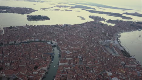 Wide-aerial-descending-shot-of-Canal-Grande-and-Ponte-di-Rialto-from-above-at-dusk,-Venice,-Italy