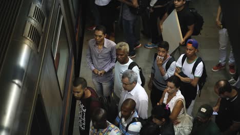 High-angle-shot-looking-down-at-people-waiting-at-a-subway-station-as-a-train-arrives