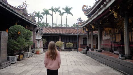 Caucasian-female-tourist-with-long-brown-hair-exploring-Dalongdong-Baoan-Temple-in-Taipei,-Taiwan