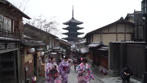 Asiatische-Touristen,-Die-Durch-Die-Straßen-Des-Geisha-viertels-Von-Kyoto-In-Japan-Spazieren-Und-Traditionelle-Kleidung-Tragen,-Kimono-Mit-Der-Yasaka-pagode-Im-Hintergrund
