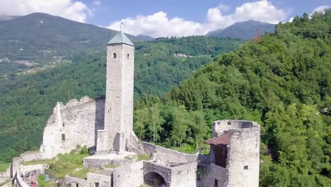 Aerial-reveal-type-shot-of-Castel-Telvana-in-Borgo-Valsugana,-Trentino,-Italy-with-drone-flying-backwards-on-a-very-clear-day
