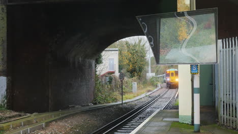Commuter-train-arriving-at-the-station-with-reflection-in-platform-mirror
