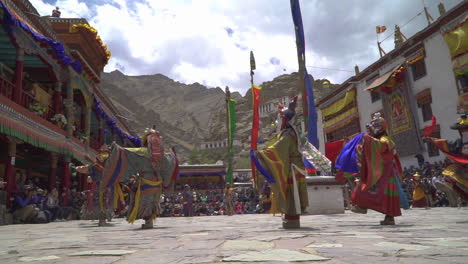 Masked-monks-dressed-in-colorful-dresses-dancing-in-Hemis-monastery-in-front-of-tourists-at-daytime