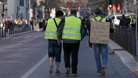 Gelbwesten-Demonstranten,-Die-Mit-Einem-Pappschild-Durch-Die-Straßen-Von-Marseille-Marschieren-Und-Den-Französischen-Präsidenten-Macron-Zum-Rücktritt-Auffordern
