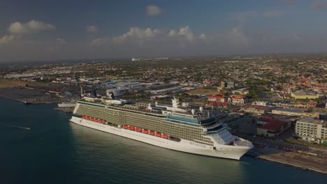 Aerial-view-of-the-cruise-ship-in-dock-with-the-island-in-the-background-and-tilting-the-camera-up-into-the-skies-4K