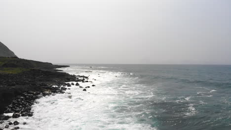 Luftaufnahmen-Von-Wunderschönen-Meereswellen,-Die-An-Der-Küste-Von-Hawaii-Mit-Bergen-Im-Hintergrund-Zusammenbrechen