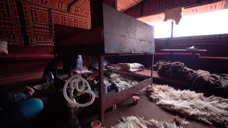 Couple-Sitting-in-a-Red-Color-Ornamented-Arabian-Tent-With-a-Burning-Fireplace-Next-to-Them