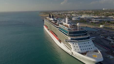Aerial-view-with-panning-movement-of-a-big-cruise-ship-in-dock-with-the-sun-shining-on-it-4K