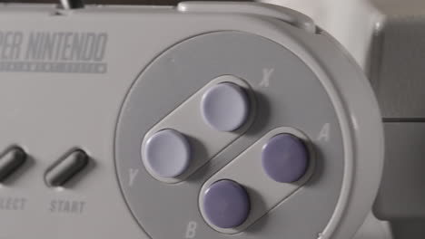 Parte-Delantera-De-La-Consola-Vintage-Super-Nintendo-Y-El-Controlador-Se-Deslizan-Hacia-La-Derecha