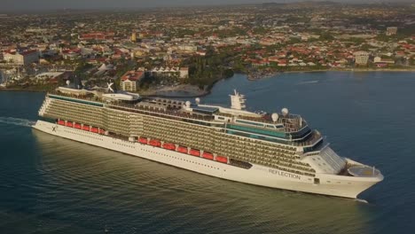 Aerial-view-of-a-big-cruise-ship-leaving-the-dock-on-a-sunny-day-with-a-slow-backwards-slide