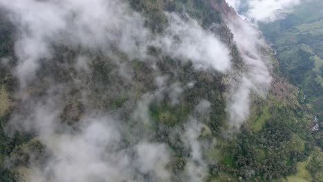 High-mountainside-in-clouds,-slow-tilt-up-aerial-shot