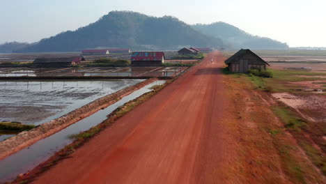 Aerial-drone-footage-moving-forward-above-a-road-surrounded-by-salt-field-near-Kampot-in-Cambodia