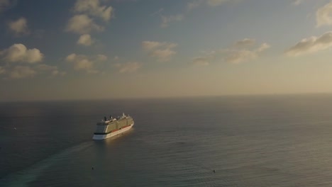 Aerial-view-of-the-cruise-ship-looking-small-sailing-into-the-big-blue-ocean